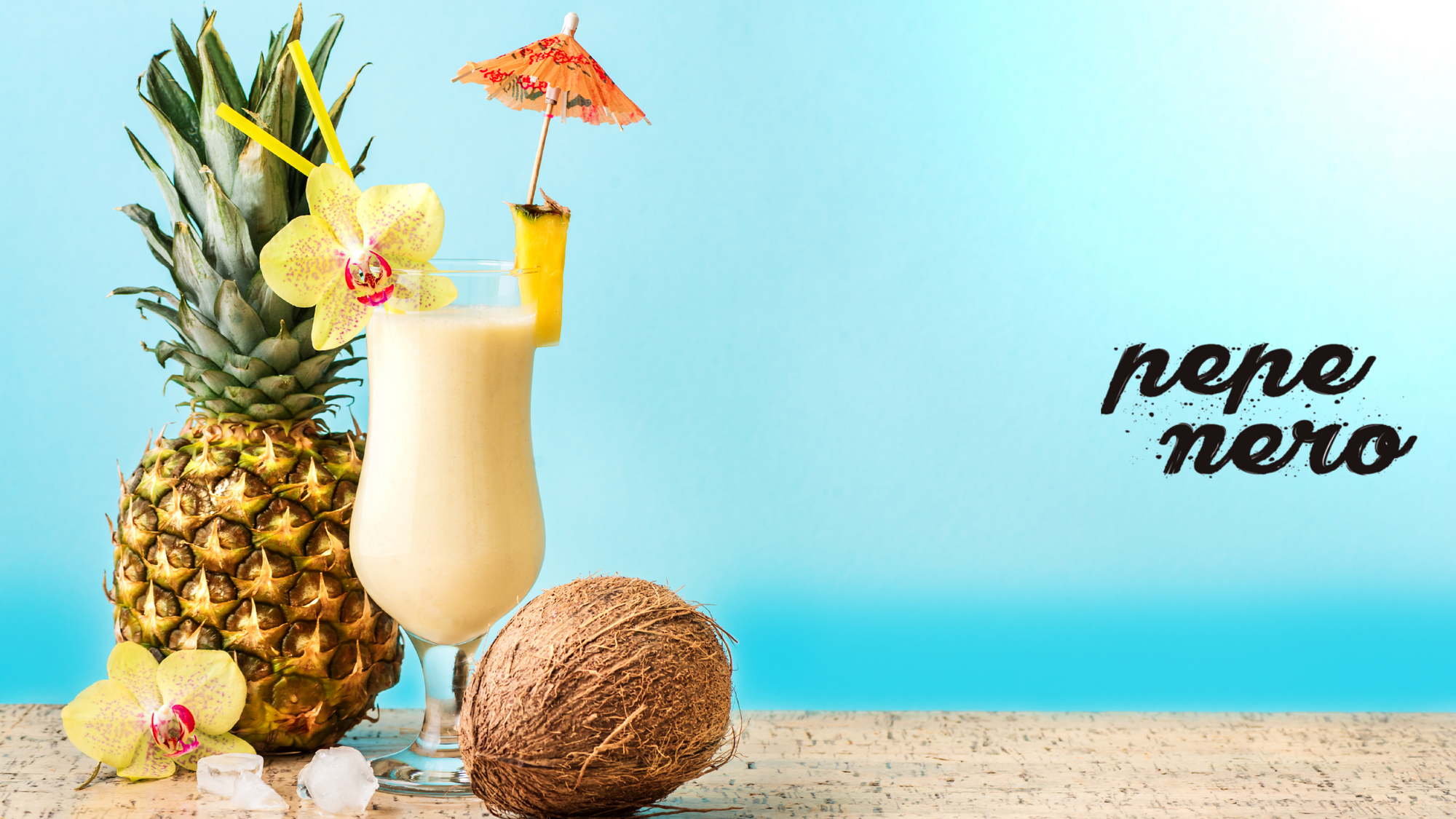 A pineapple and coconut next to a Piña Colada with a paper umbrella