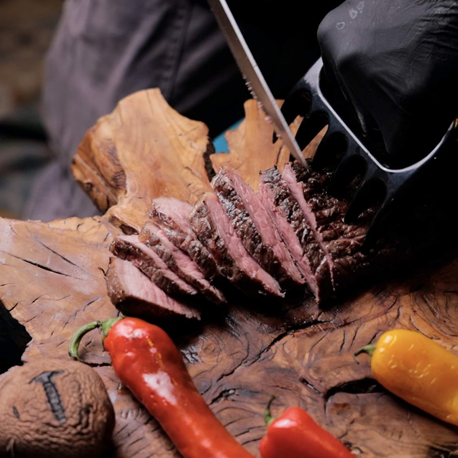 Slicing meat on an olive cutting board using the bear claw from the Pepe Nero BBQ set
